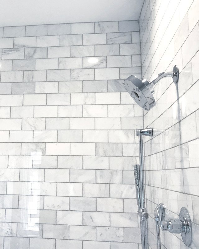 Bath remodel in Arlington, VA showcasing white and gray shower tiles with a metallic shower head.