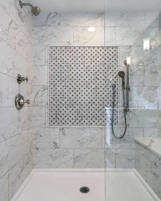 A welcoming walk-in shower accented with exquisite Carrera marble surround, located in Arlington, VA.