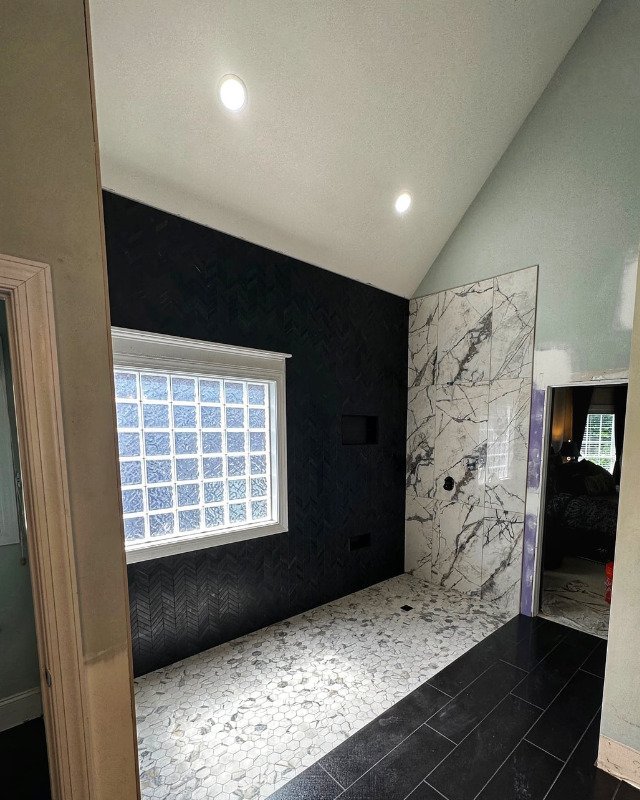 Bathroom renovation in Arlington, VA featuring a large walk-in shower with black herringbone tile walls and a white accent tile floor.